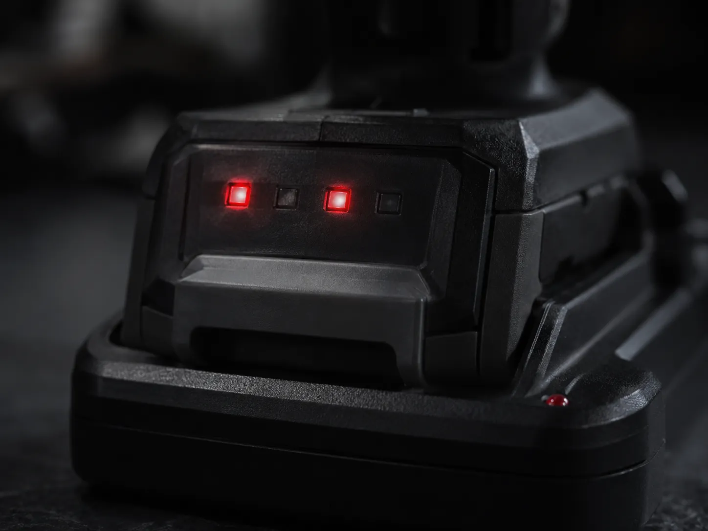Cordless vacuum battery pack on its charger with the first and third indicator lights glowing red after 12 hours of charging.