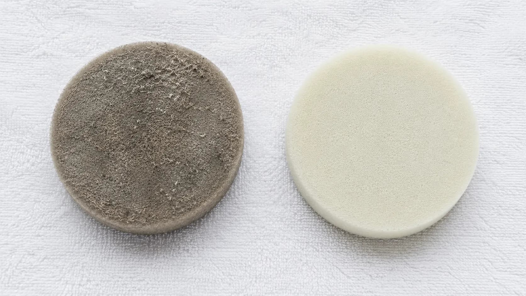 Dirty grey vacuum foam filter beside a clean rinsed foam filter on a white towel, showing before-and-after filter cleaning results.