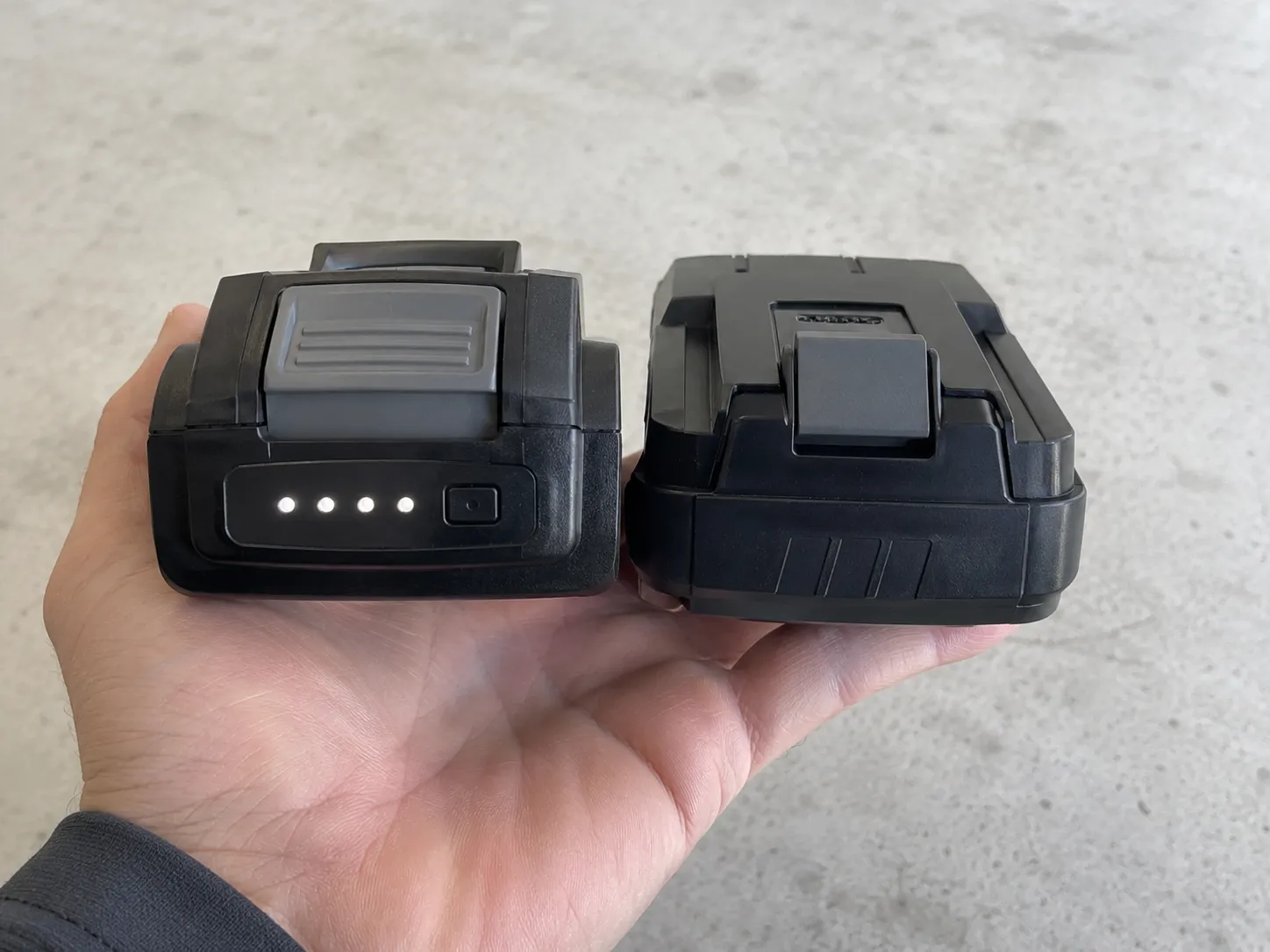 Two cordless vacuum battery packs held side by side, with only the left pack featuring a four-light fuel gauge and indicator button.