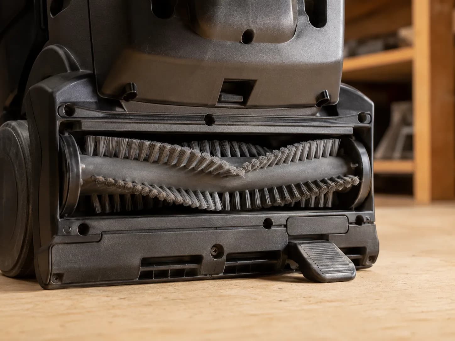 Close view of an upright vacuum nozzle with the brush roller stopped and the foot pedal pressed down, showing that the brushroll is switched off rather than broken.