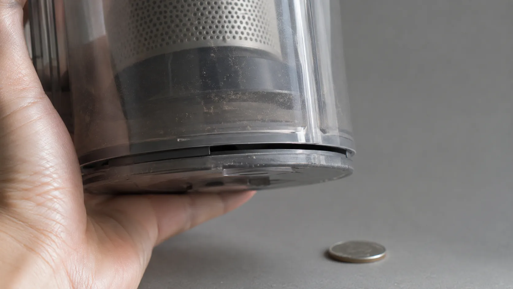 Close-up of a clear vacuum dirt cup with its bottom flap sitting about 2 mm proud of the seal, creating a narrow gap that reduces airflow.