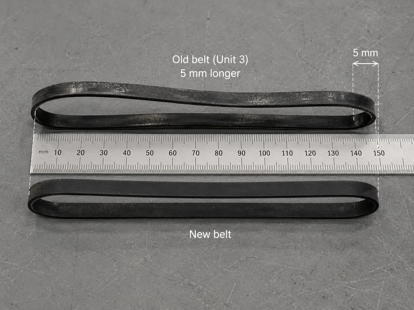 Old vacuum belt measured against a steel rule beside a new belt, showing a 5 mm stretch that caused slipping without breaking.
