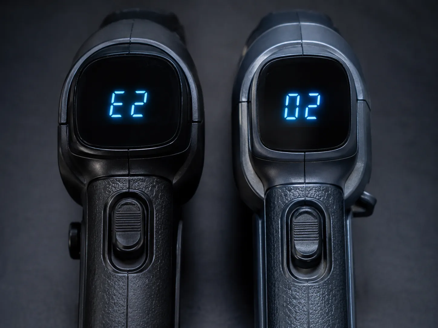 Close-up of two Shark-style cordless vacuum handle displays showing a short fault code and a numeric message during fault reproduction testing.