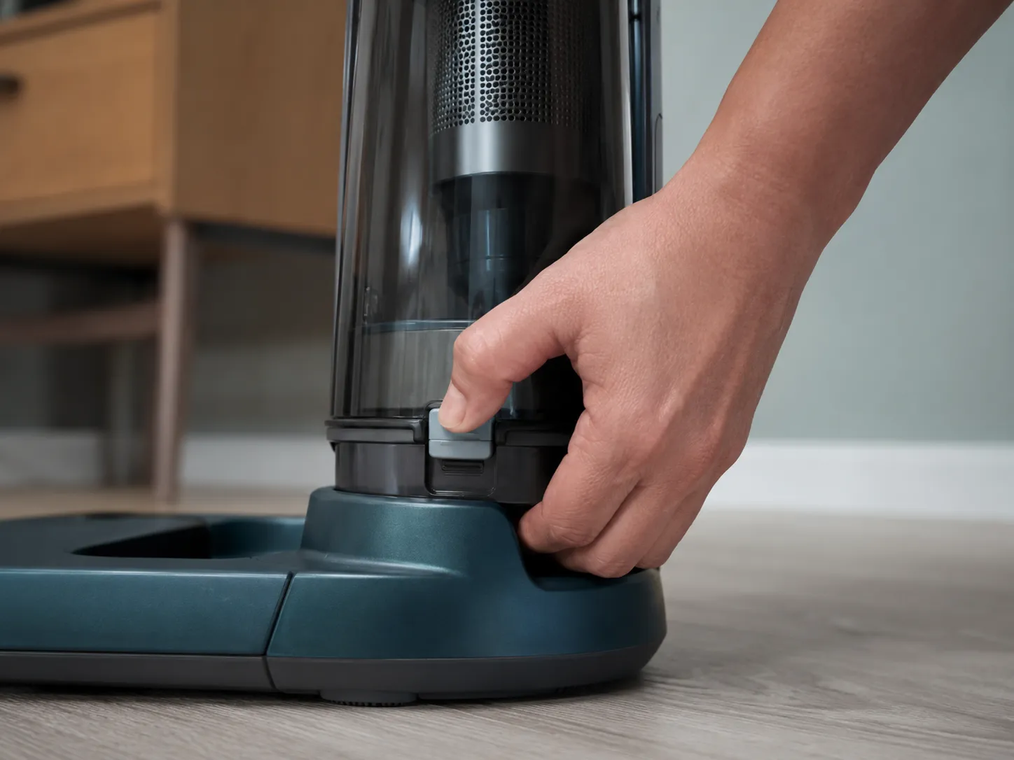 Hand pressing a cordless vacuum Lift-Away pod onto the floor base until the latch clicks into place, showing the release catch and connection seam in close-up.