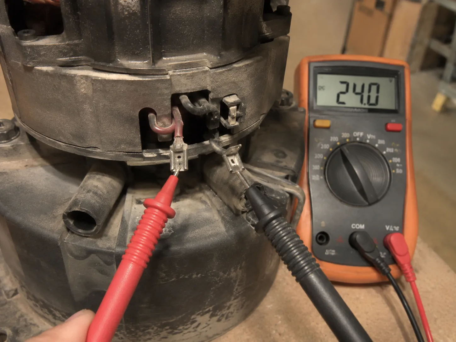 Disconnected low-voltage terminals on a Beam central vacuum unit tested with multimeter probes showing a 24-volt reading.