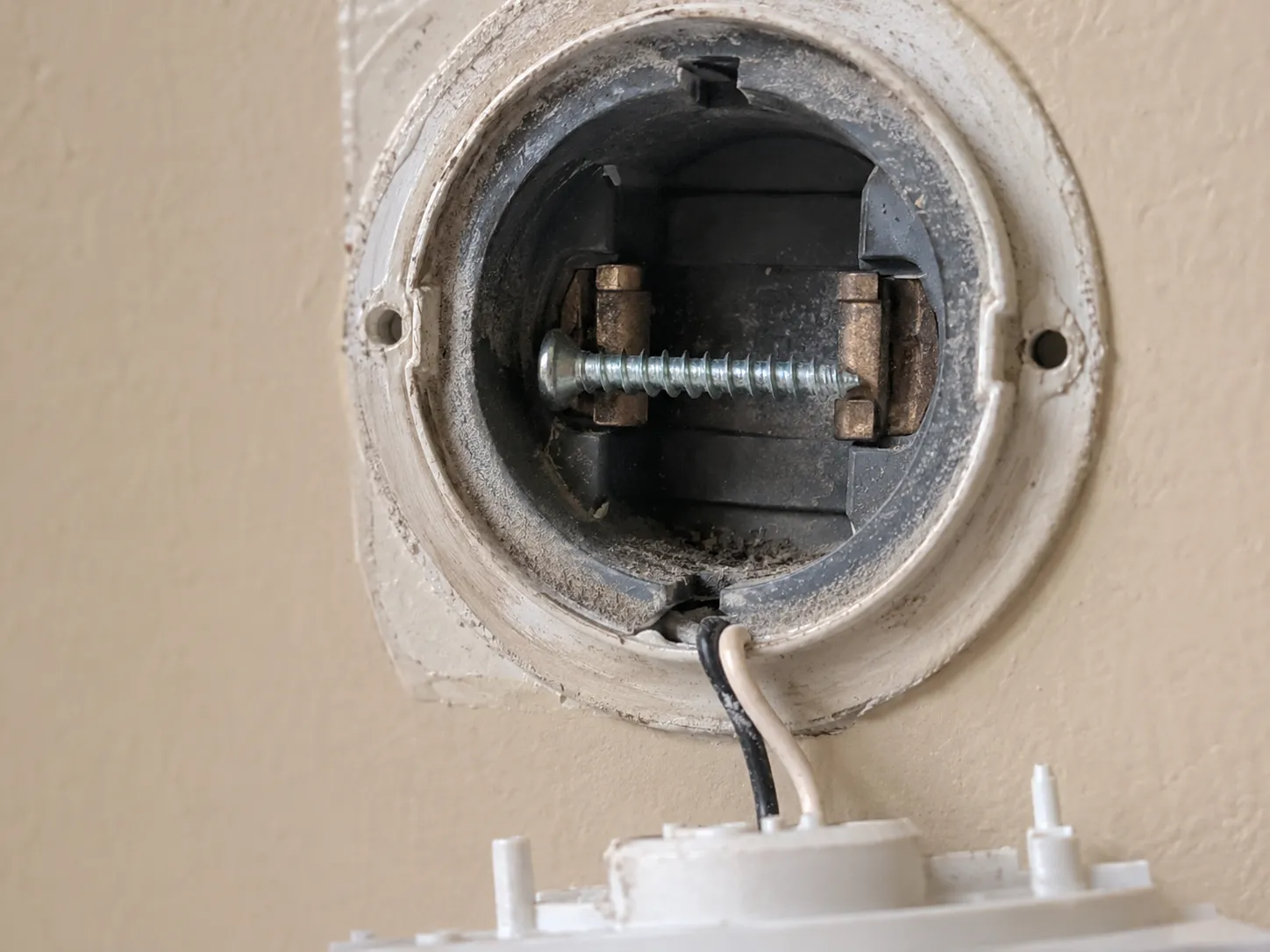 Opened Beam central vacuum wall inlet with a stray screw bridging the internal metal contacts before removal.