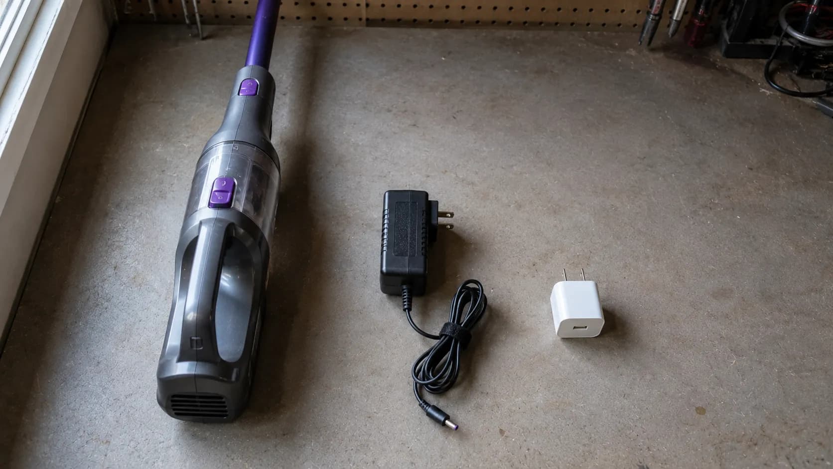 Cordless vacuum, charging adapter and phone charger arranged on a workbench to illustrate the recommended outlet, charger and battery troubleshooting order.