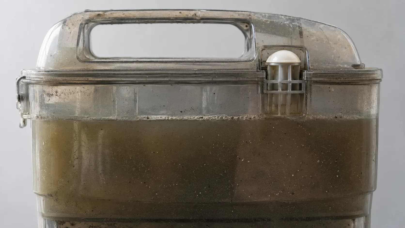 White float raised to the top of a full Bissell CrossWave dirty-water tank, showing the automatic suction shutoff triggered by murky wastewater.