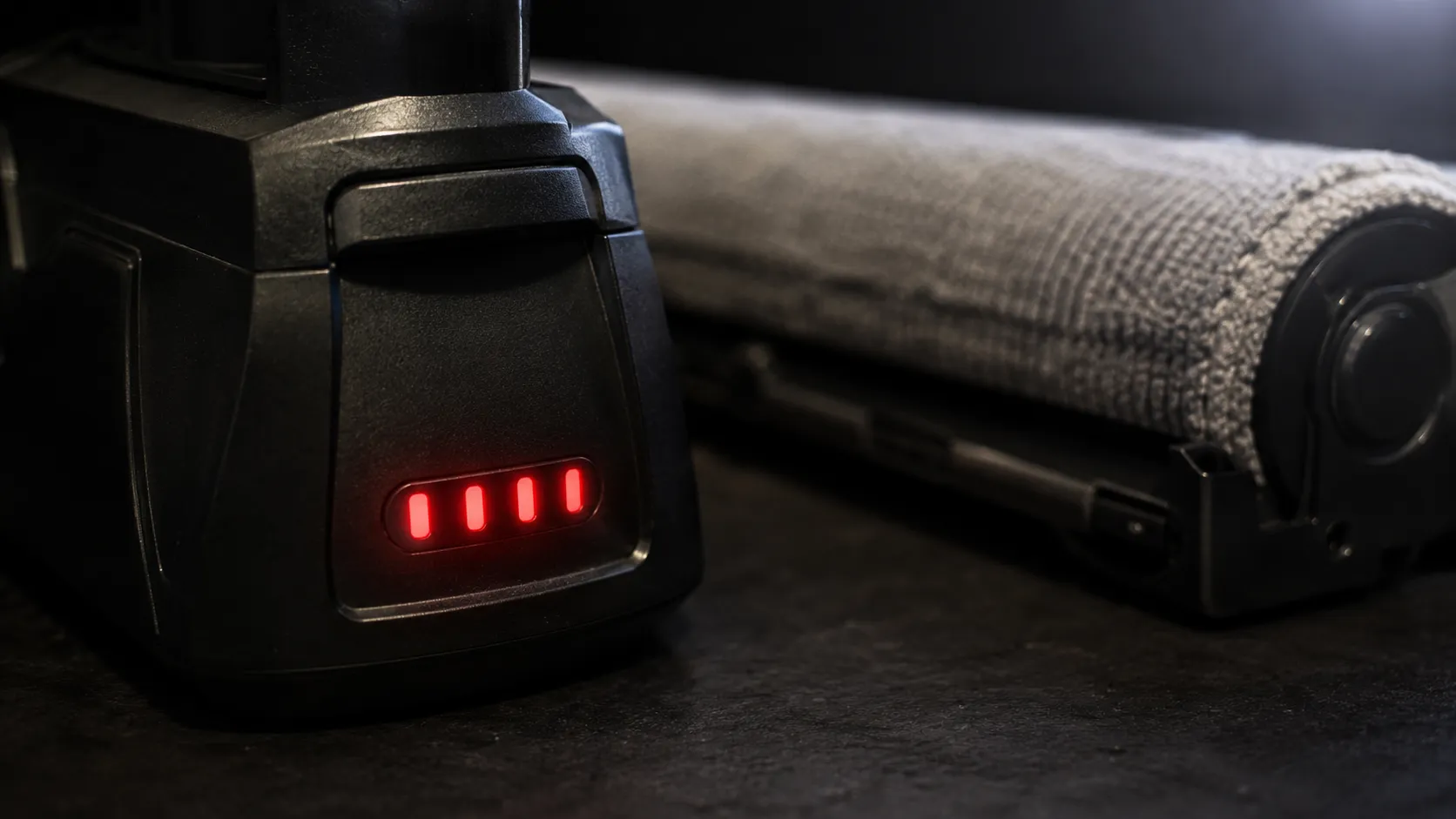 Bissell Multi Reach cordless vacuum showing four solid red battery lights with a grey microfibre cloth jammed around the brushroll.