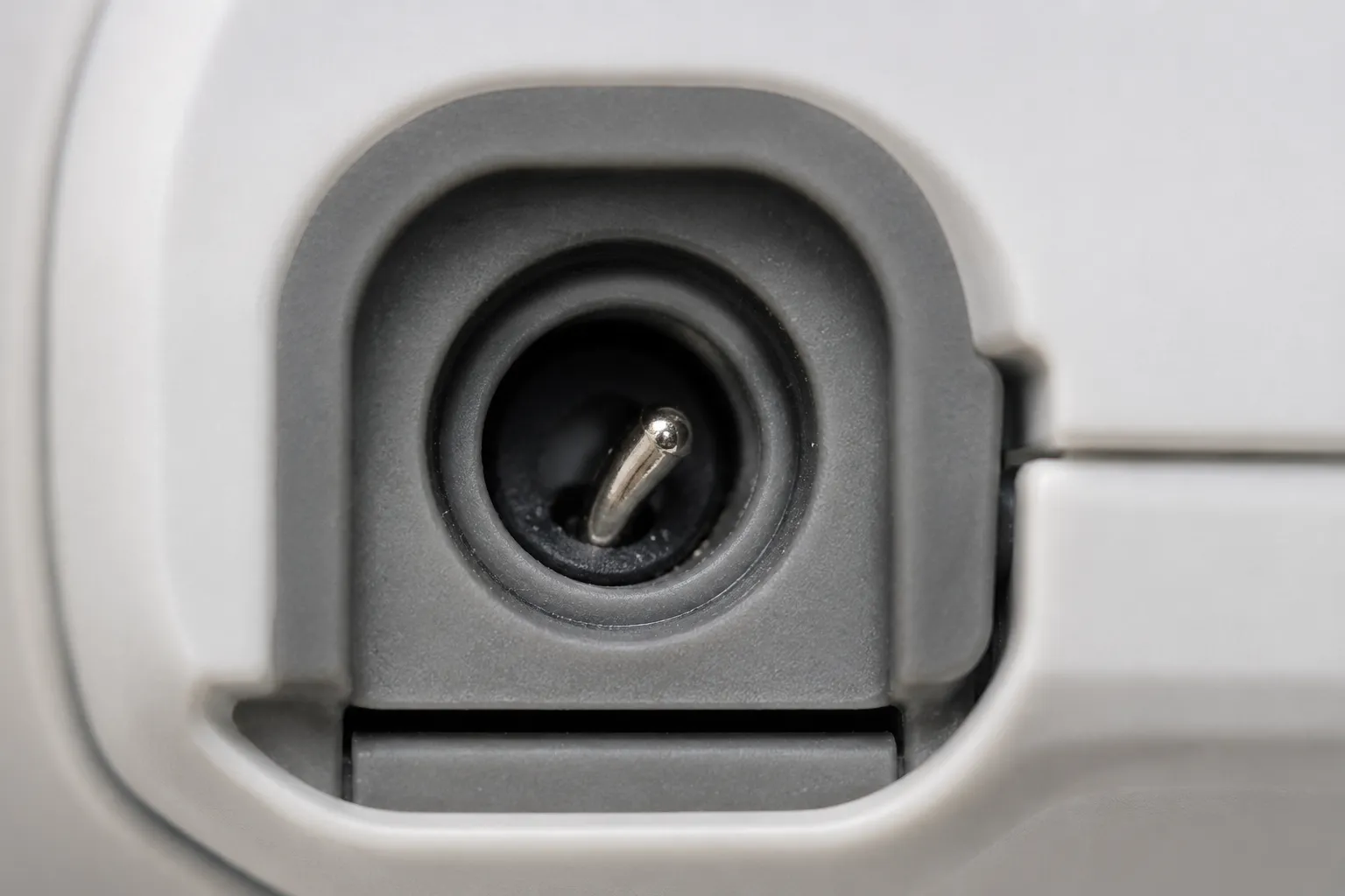 Extreme close-up of a cordless vacuum charging port showing a slightly bent metal contact pin inside the recessed socket.
