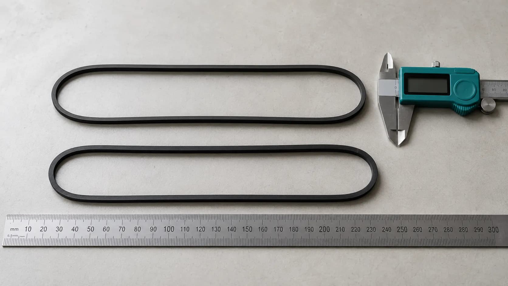 Type U and E0205 vacuum belts laid side by side with a ruler and digital caliper, showing the eight millimetre size difference between the two non-interchangeable belts.