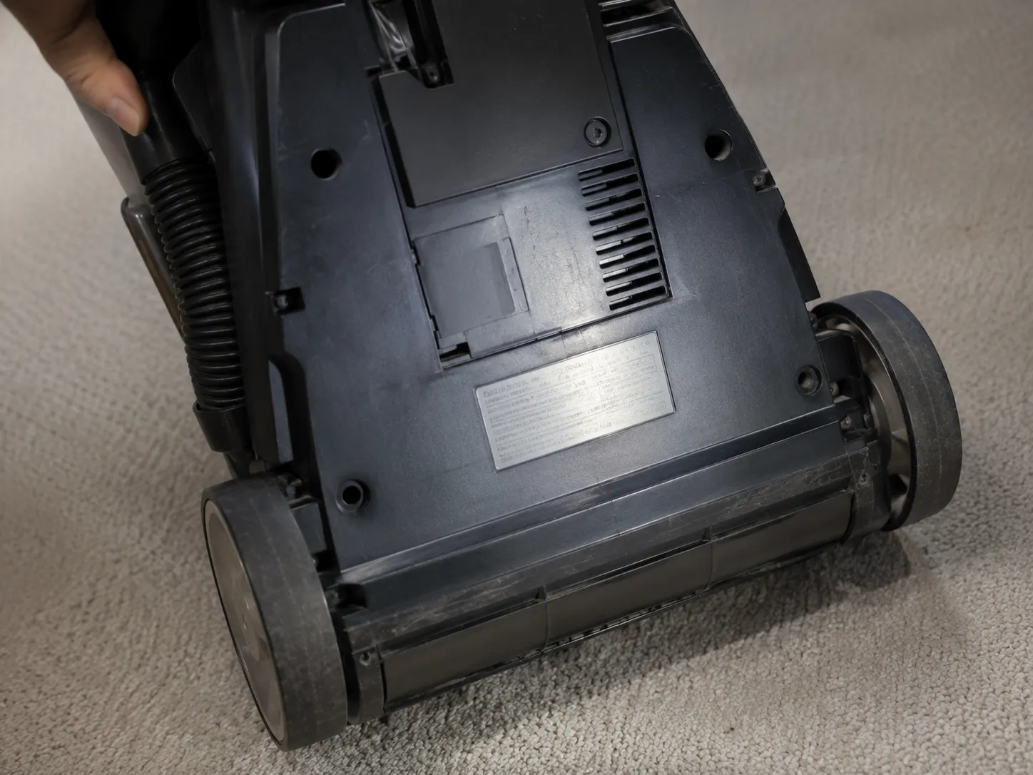 Close-up of the lower rear specification label on an upright vacuum, showing where to find the model number and manufacturing code.