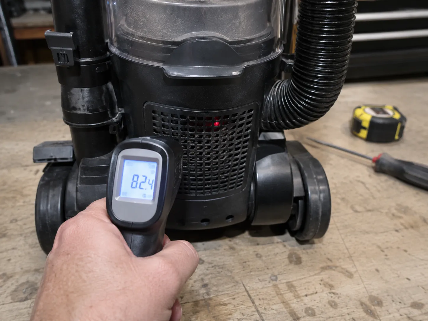 Infrared thermometer measuring the exhaust housing temperature of an upright vacuum at the moment its thermal cut-out trips.