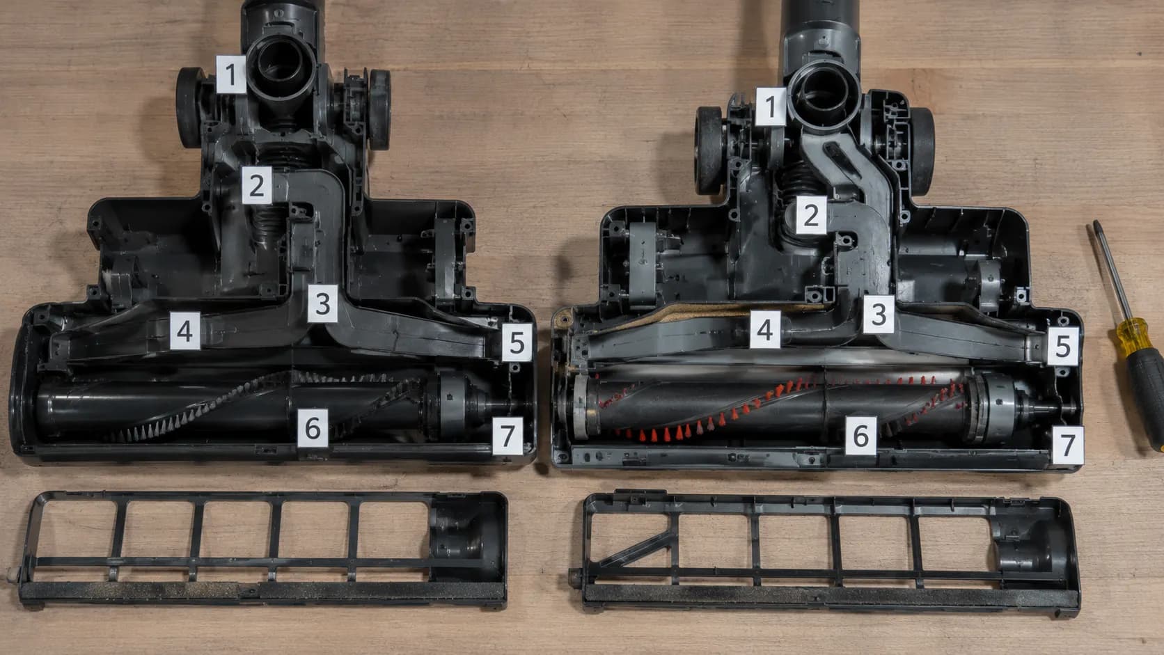 Two disassembled upright vacuum cleaning heads placed side by side on a wooden workbench, with internal airflow channels exposed and numbered markers identifying key junctions.
