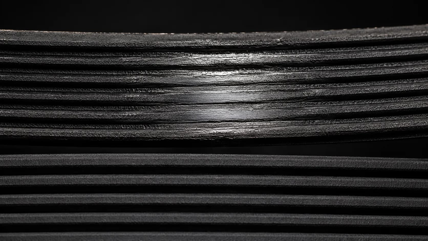 Extreme close-up of a worn grooved vacuum belt with a glossy polished centre beside a new belt with crisp matte ribs, showing how glazing causes slipping without snapping.