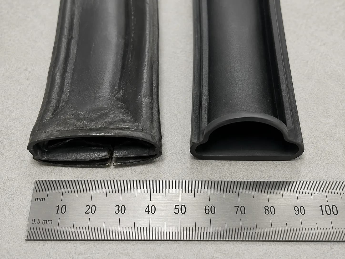 Overhead comparison of a compressed, split Roomba bin skirt beside a new upright seal, with a steel ruler included for scale.