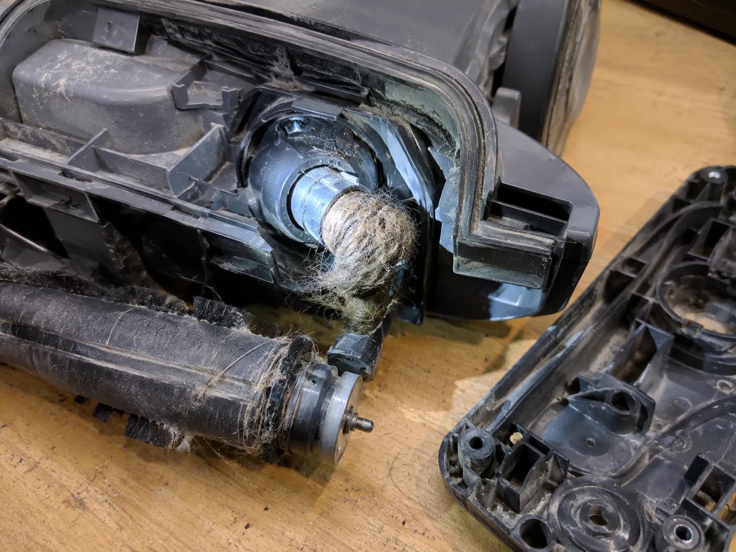 Hair and lint clog wedged in the Shark vacuum brush roll coupling elbow after base plate removal.