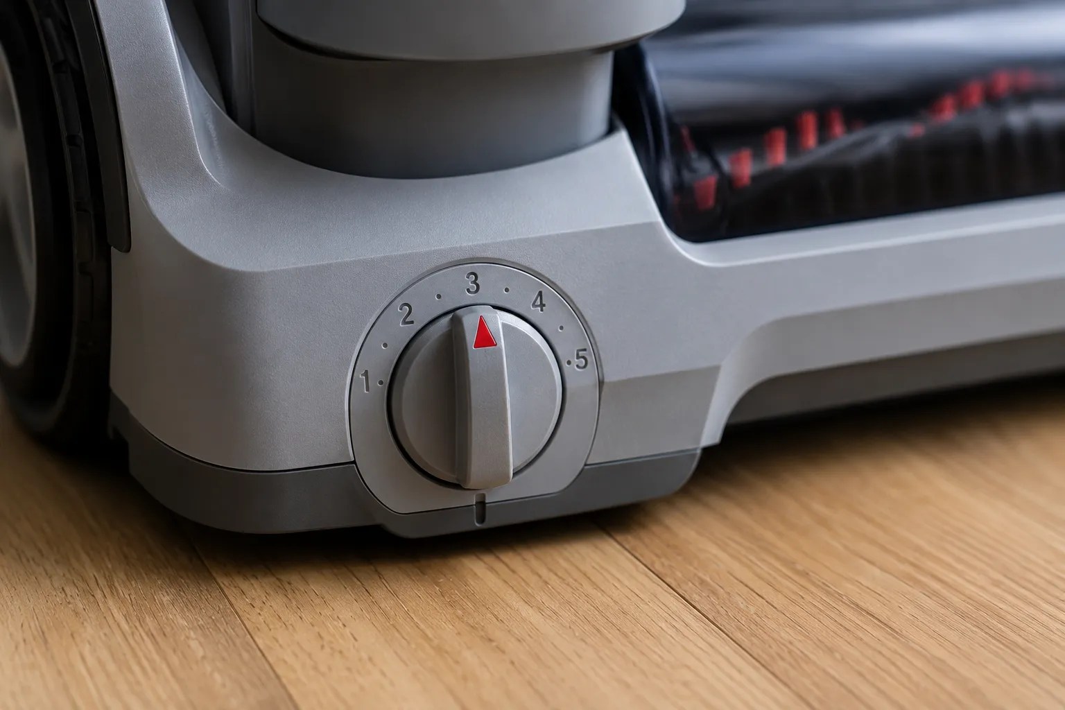 Close-up of a numbered upright vacuum height adjustment dial with a red pointer set to position three on the machine’s base.