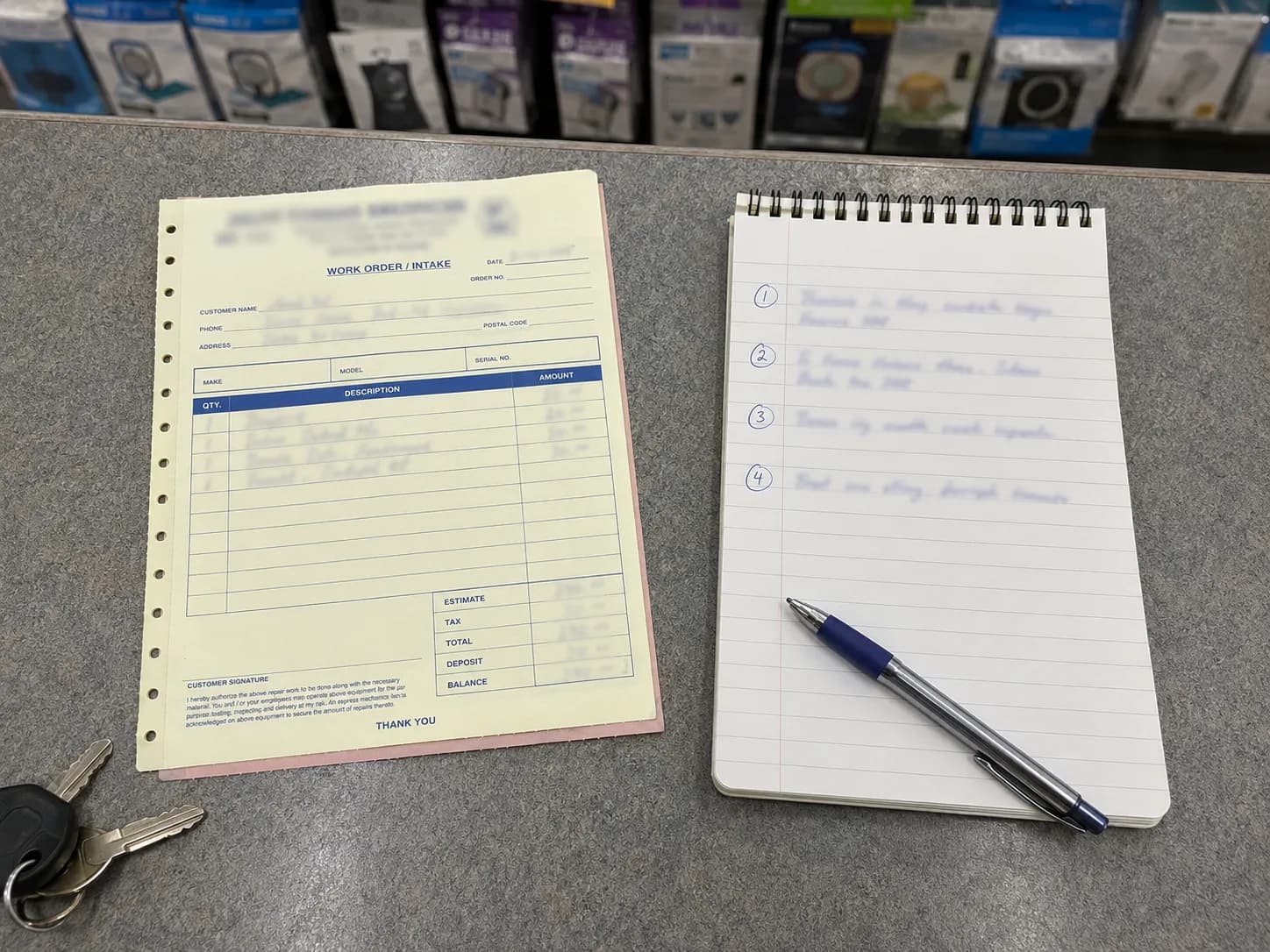 Vacuum repair service intake ticket beside a notepad listing four answers from the counter, with a pen and car keys on a shop counter.