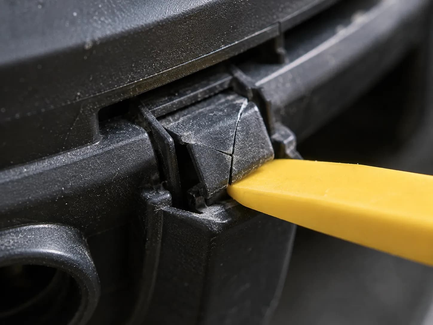 Cracked snap-fit plastic clip on a vacuum housing during a careful teardown.